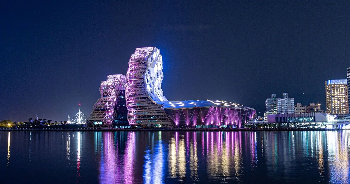 Kaohsiung Music Center illuminated in purple and reflected in Love River Bay